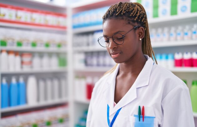 African american woman pharmacist standing with serious expression at pharmacy